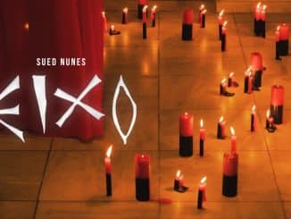 Imagem promocional do videoclipe "EIXO" de Sued Nunes, com velas vermelhas e pretas acesas no chão em um ambiente sombrio, com o título do clipe em destaque.